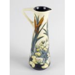 A William Moorcroft ewer, of slender tapering form, decorated with scene of lilies and reeds upon