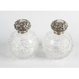 A pair of early 20th century hallmarked silver topped cut glass scent bottles, each with globular