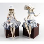 Two Lladro figures, each similarly modelled as young girls in frilled dresses playing with dolls,