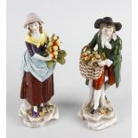 A pair of Capodimonte porcelain figures, modelled as male and female fruit sellers, he with wicker