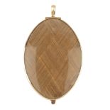 A late 19th century gold mourning pendant. Designed as an oval-shape woven hair glazed panel, with