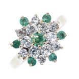 A 9ct gold emerald and cubic zirconia cluster ring. The circular-shape emerald, within a series of