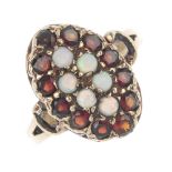 A 9ct gold opal and garnet cluster ring. The circular opal cabochon marquise-shape panel, within a