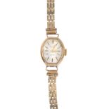 A 9ct gold watch. A lady's wristwatch. the barrel-shape cream dial with baton hour markers, to the