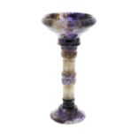 A Blue John pedestal cup The flared bowl, shading from clear to dark amethyst, with ribbed collar on