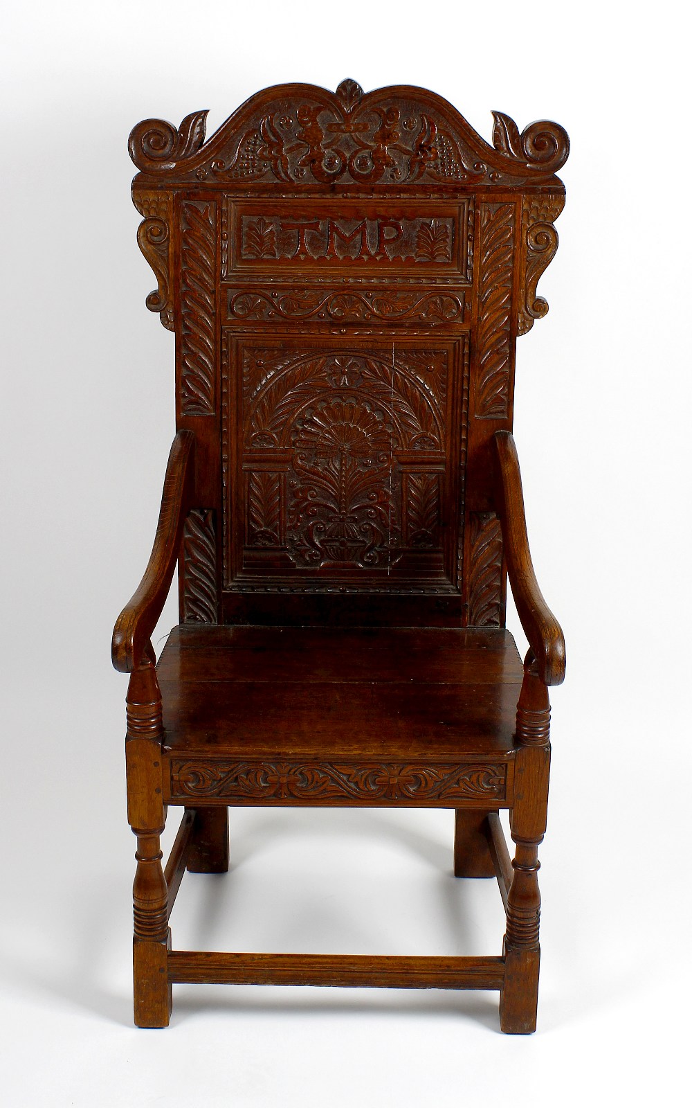 An early 20th century carved oak Wainscot-style chair. The foliate scrolling crest above carved back