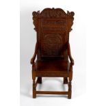 An early 20th century carved oak Wainscot-style chair. The foliate scrolling crest above carved back