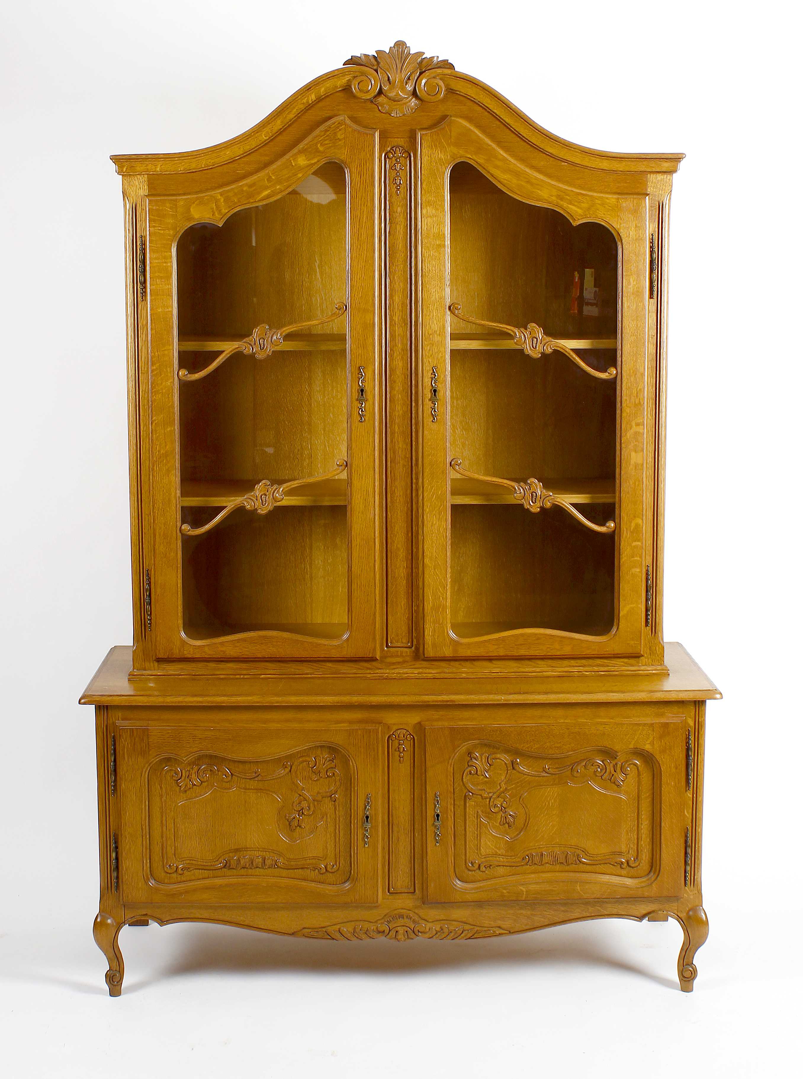 A reproduction oak display cabinet. The upper section with carved scrolled pediment above twin