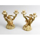 A pair of James Hadley Royal Worcester candlesticks, modelled as a young male and female