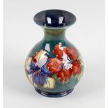 A Moorcroft pottery vase. The bulbous body with flared neck, finished in a blue and green merging