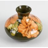 A Moorcroft pottery vase. Of compressed bulbous form, finished in a green glazed ground decorated in