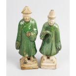 A pair of Chinese Ming dynasty pottery figures. Depicting male attendants, each draped in a green
