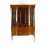 An early 20th century inlaid mahogany display cabinet. The moulded breakfront cornice over chequer-