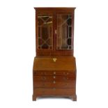 A George III mahogany bureau bookcase. The upper stage with dentil cornice over a pair of astragal-