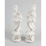 A pair of blanc de chine figures. Each modelled as female wearing flowing robes and holding lotus