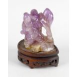 An antique Chinese carved amethyst figure group, depicting two children upon a naturalistic modelled