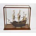 A carved and painted wooden model of The Golden Hind. With stitched linen cloth sails above a