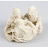 A Meji period ivory netsuke. Modelled as parents cradling a young child, incised signature