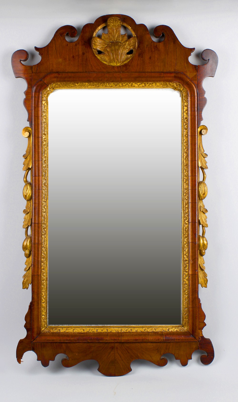 A Georgian wall mirror. The rectangular bevelled plate within scroll carved mahogany frame having