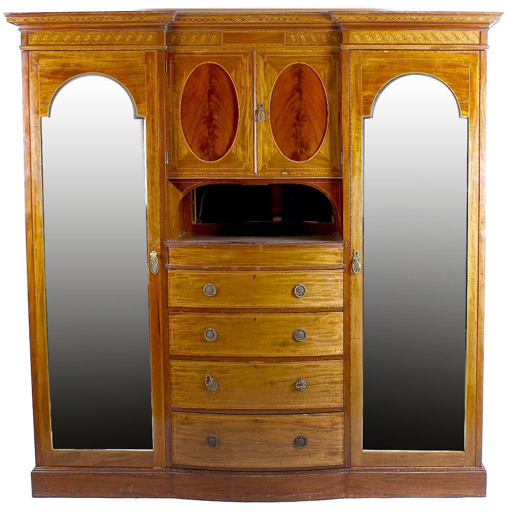 A large inlaid wardrobe. Of inverted break form form having central twin door cupboard above inset