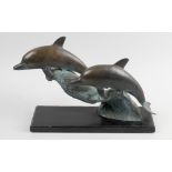 A bronzed copper group of two dolphins. Modelled jumping through waves, with verdigris to sea,