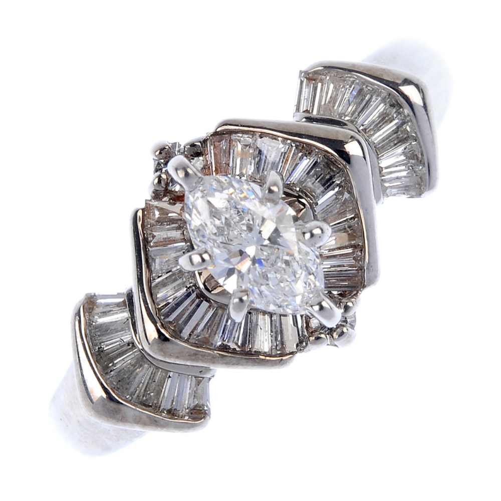 A diamond dress ring. The marquise-shape diamond, with tapered baguette-cut diamond chevron