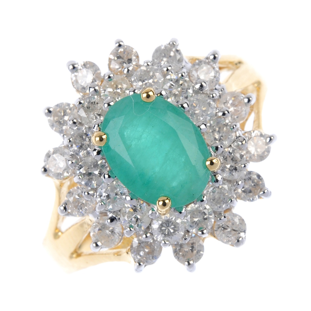 An 18ct gold emerald and diamond cluster ring. The oval-shape emerald, within a brilliant-cut
