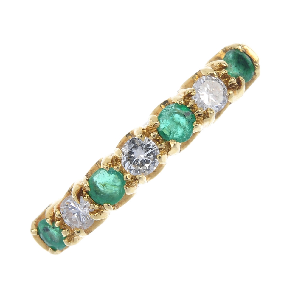 An 18ct gold emerald and diamond seven-stone ring. The alternating brilliant-cut diamond and