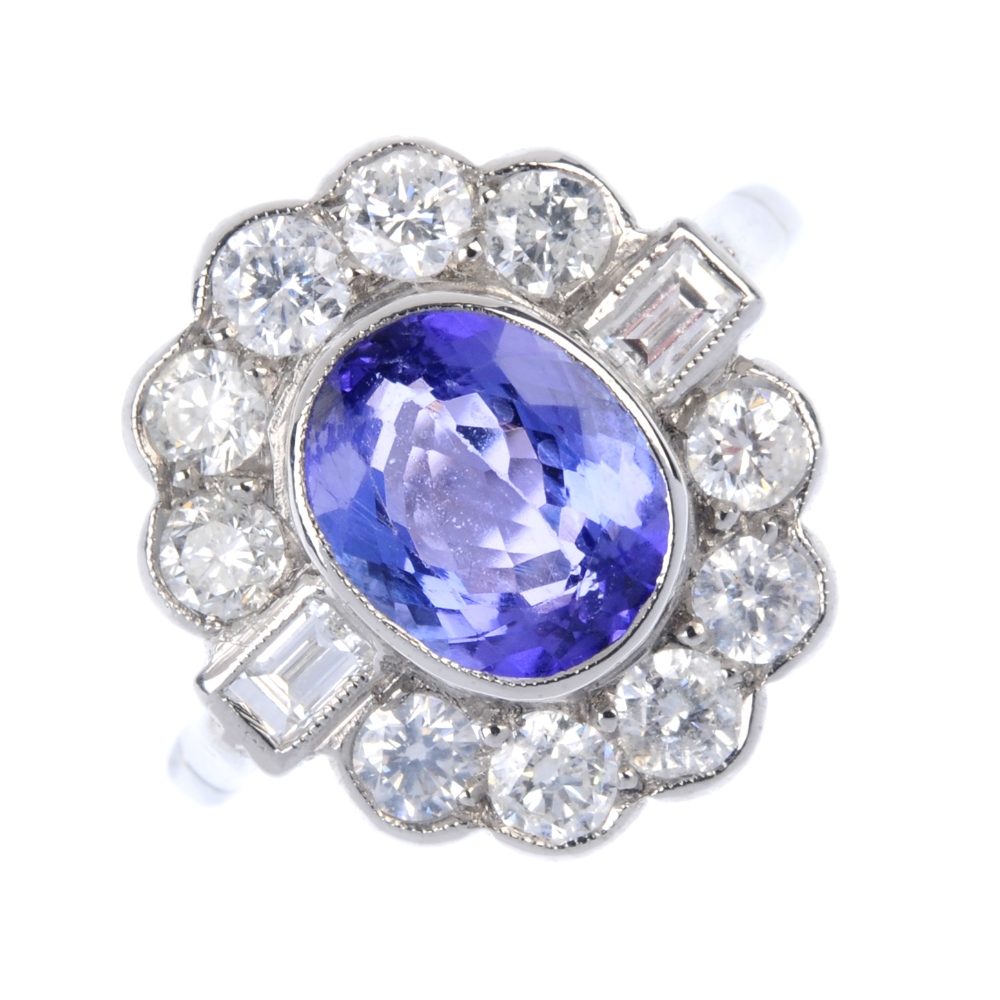 A tanzanite and diamond cluster ring. The oval-shape tanzanite collet, within a brilliant-cut