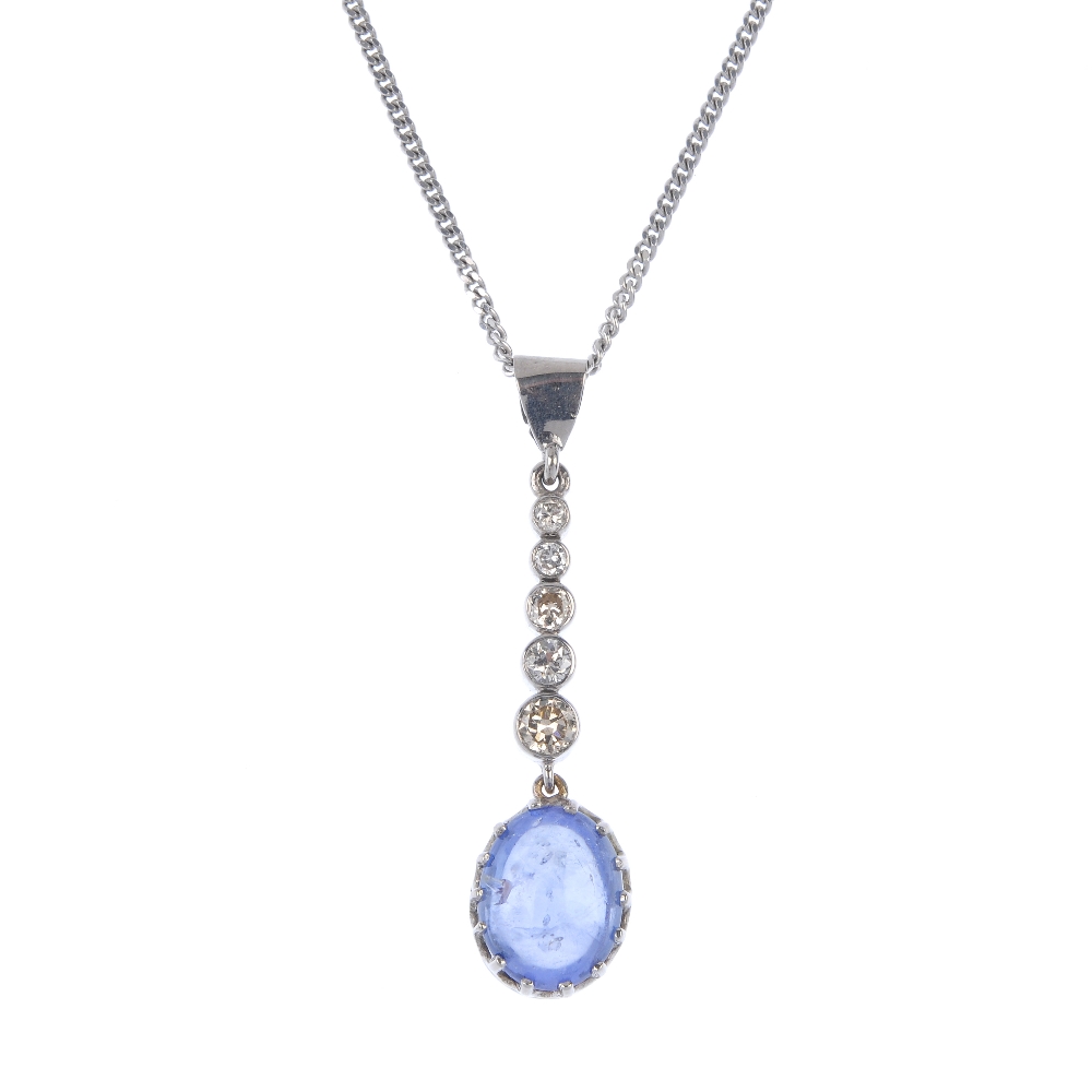 A sapphire and diamond pendant. The oval sapphire cabochon, suspended from a graduated brilliant-cut