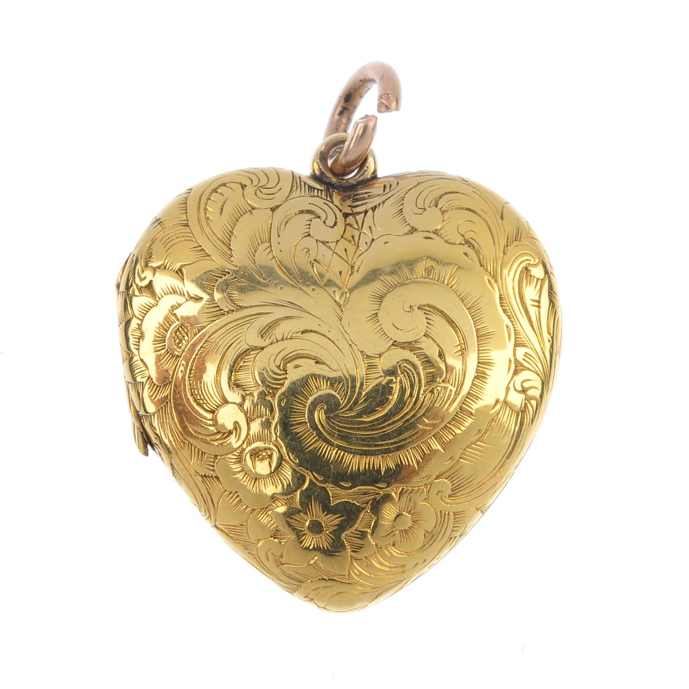 An early 20th century gold heart locket. The scroll engraved front panel, opening to reveal a