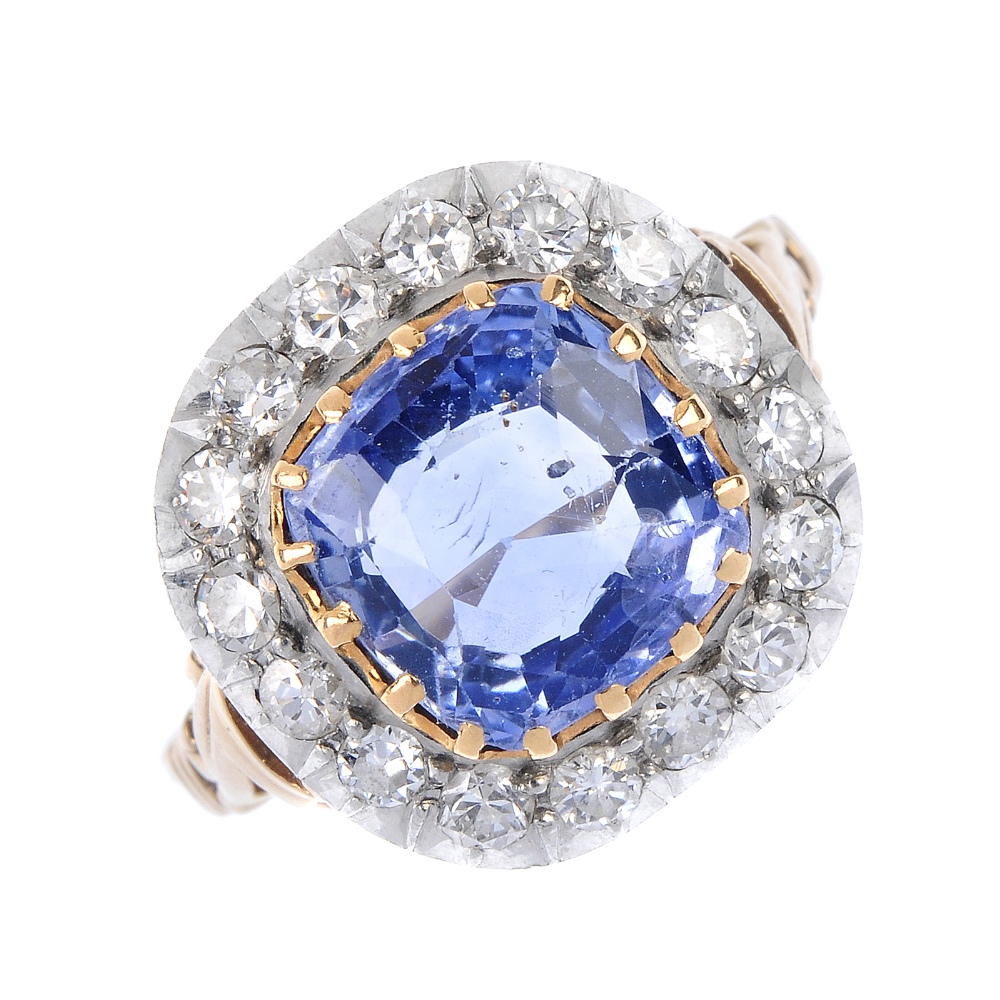 An early 20th century gold and silver sapphire and diamond cluster ring. The cushion-shape sapphire,