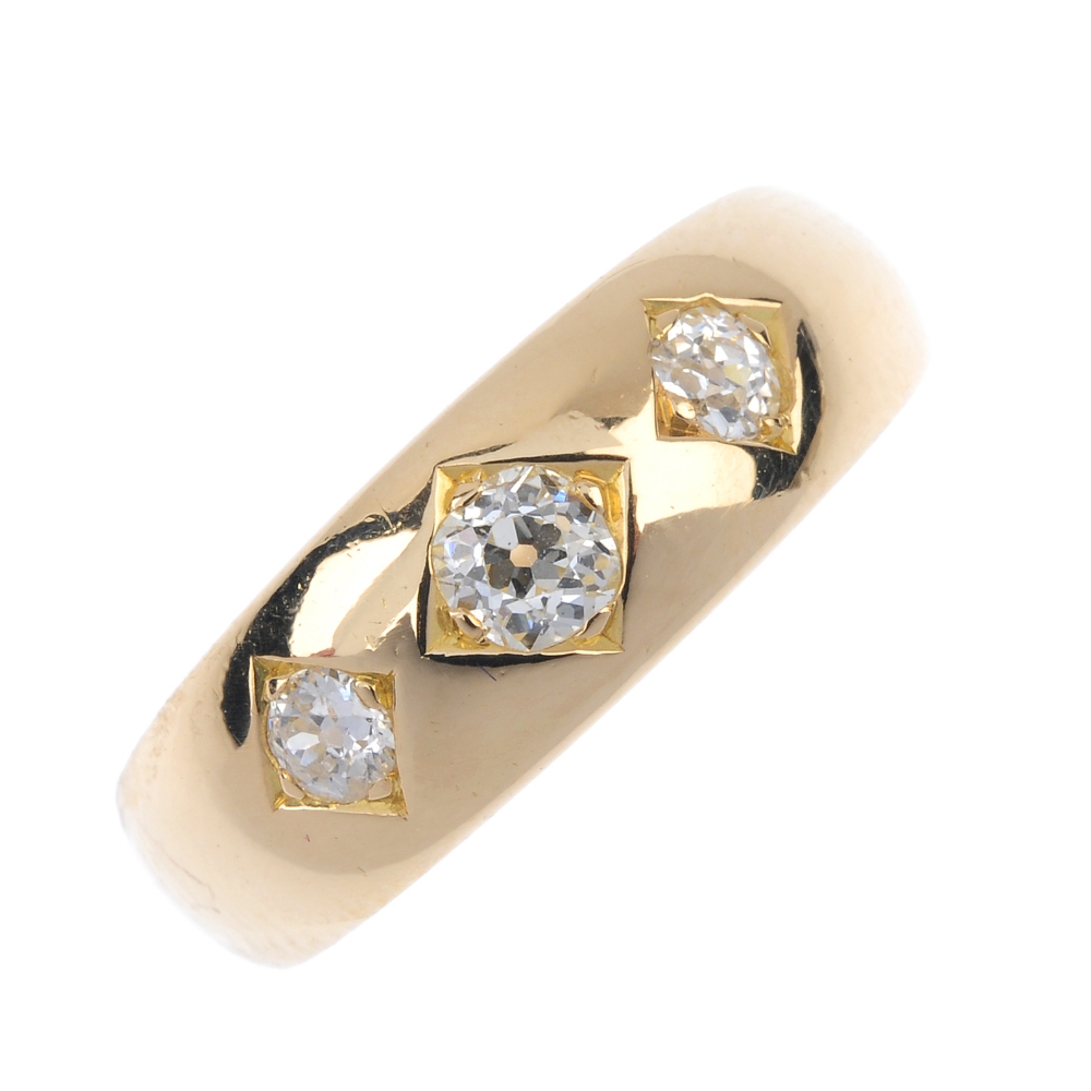 A late Victorian 18ct gold diamond three-stone ring. The graduated old-cut diamond line, inset to