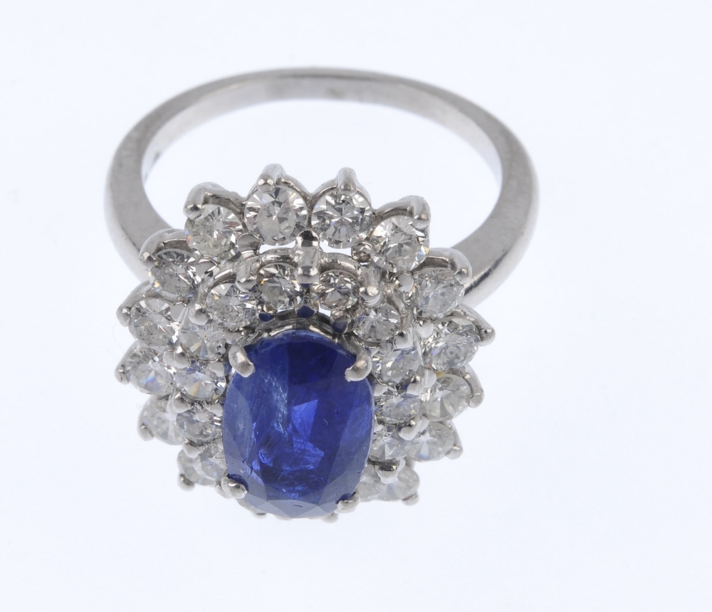 A sapphire and diamond cluster ring. The oval-shape sapphire, within a brilliant-cut diamond - Image 2 of 4