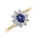 An 18ct gold sapphire and diamond cluster ring. The oval-shape sapphire, within a brilliant-cut