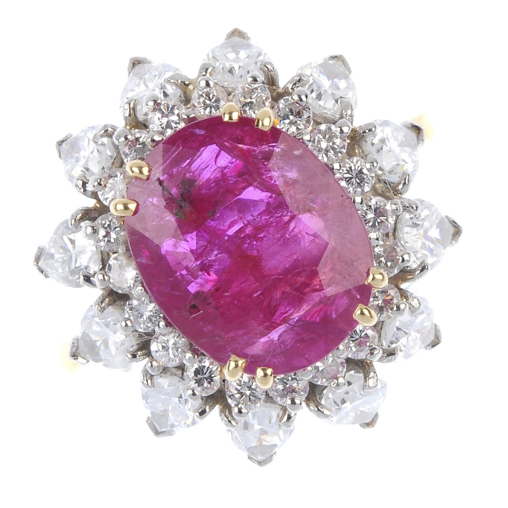 A ruby and diamond floral cluster ring. The oval-shape ruby, within a brilliant-cut diamond
