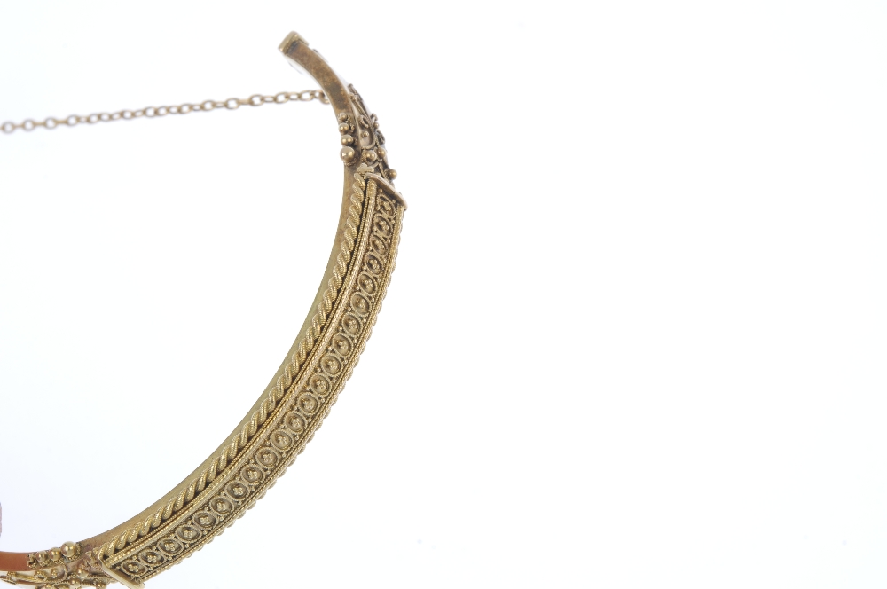 A late 19th century gold hinged bangle. The beaded motif, to the rope-twist border and scrolling - Image 2 of 3