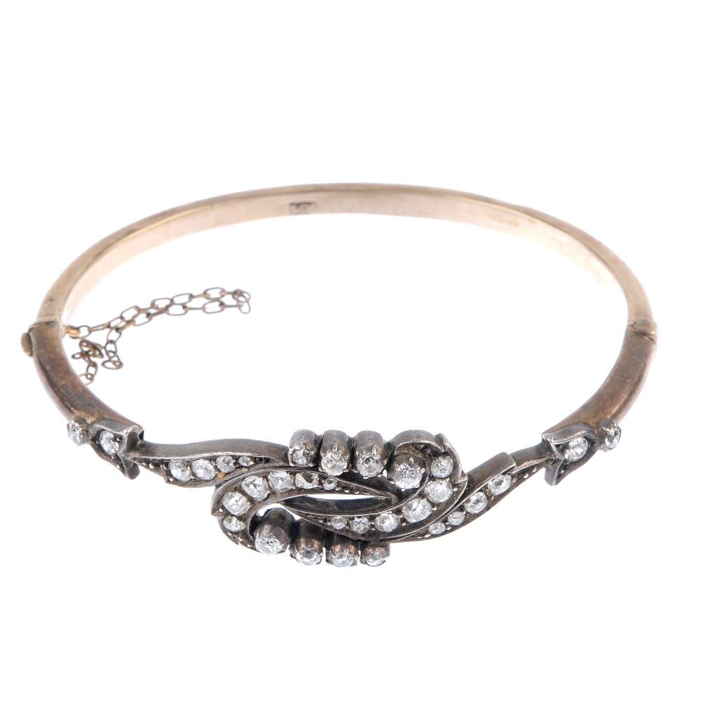 A late 19th century silver and gold diamond hinged bangle. The front of openwork design, with