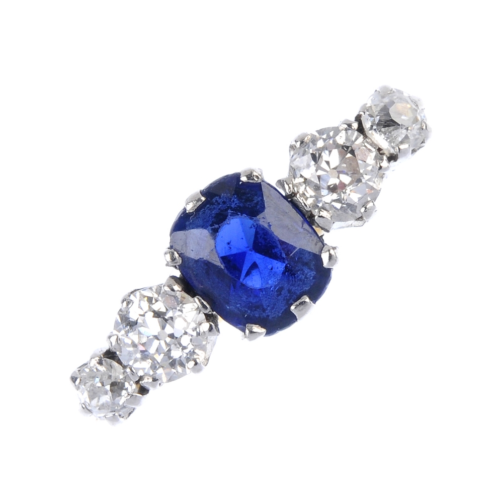 An 18ct gold sapphire and diamond five-stone ring. The oval-shape sapphire, with graduated old-cut