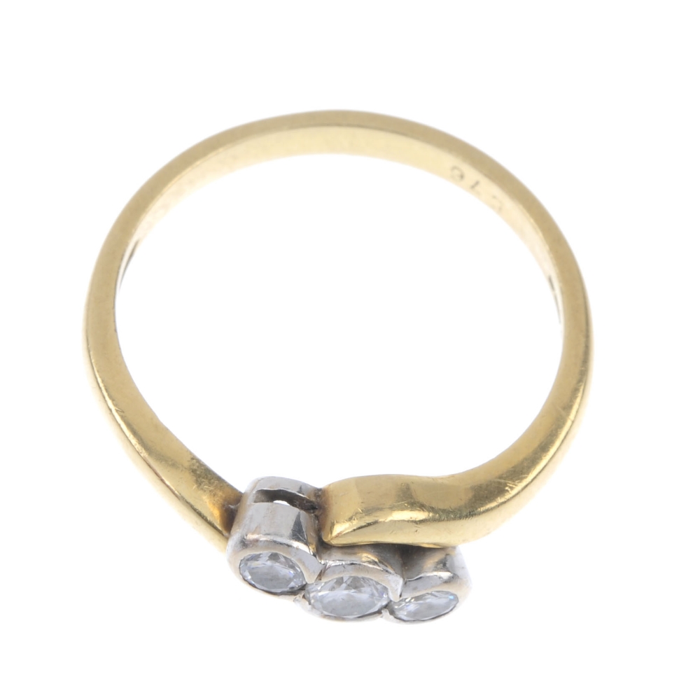 An 18ct gold diamond three-stone crossover ring. The graduated brilliant-cut diamond collets, to the - Image 2 of 4