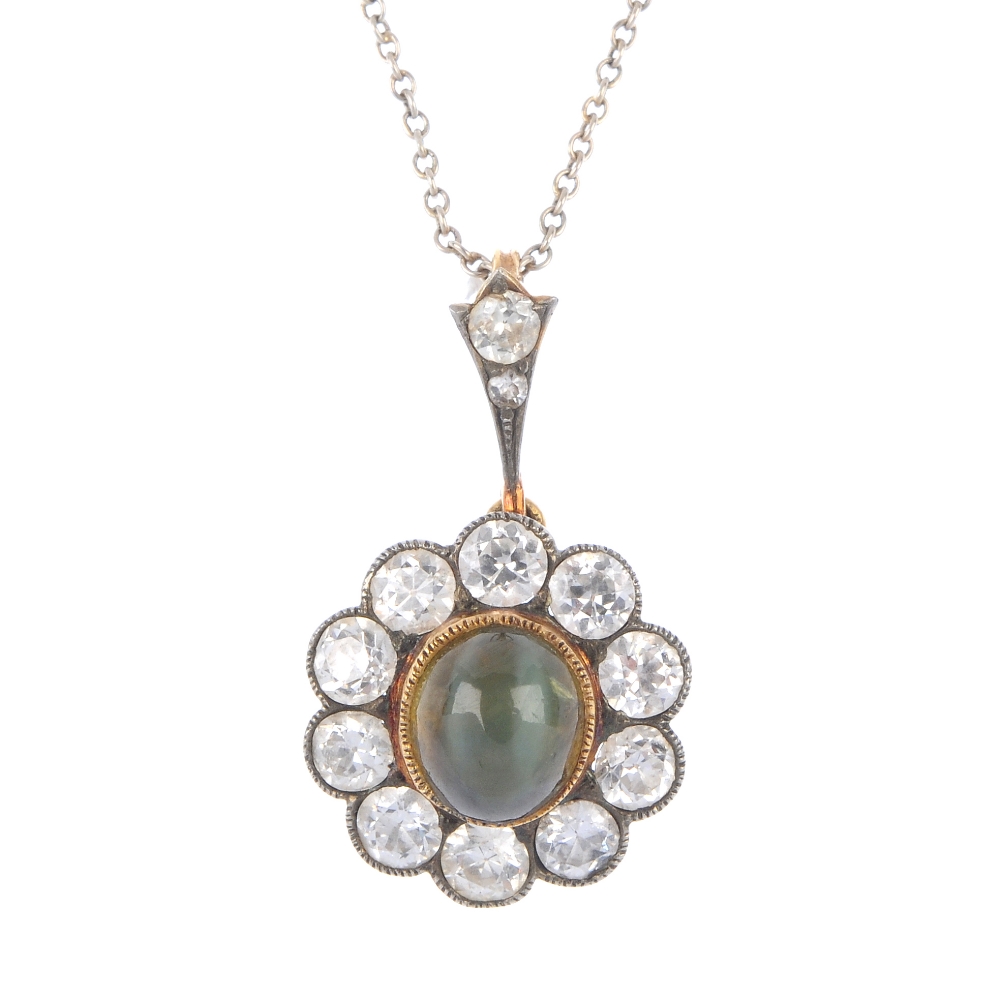 An early 20th century gold cat's-eye chrysoberyl and diamond cluster pendant. The oval cat's-eye