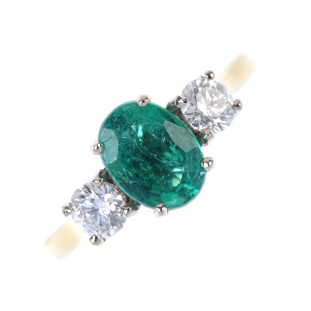 * An 18ct gold emerald and diamond three-stone ring. The oval-shape emerald, to the brilliant-cut