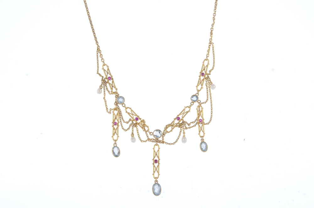 An aquamarine, ruby and seed pearl necklace. The front designed as a series of alternating