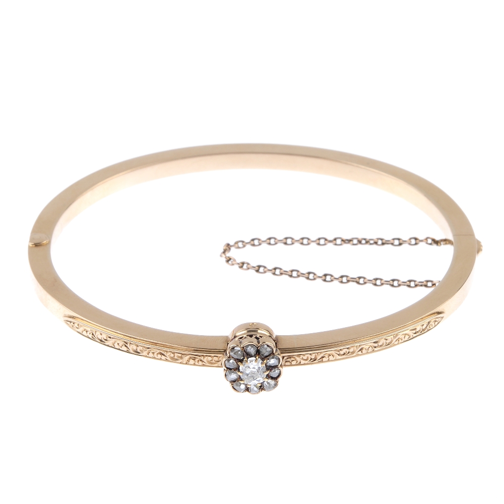An early 20th century gold diamond hinged bangle. The old-cut diamond, within a rose-cut diamond