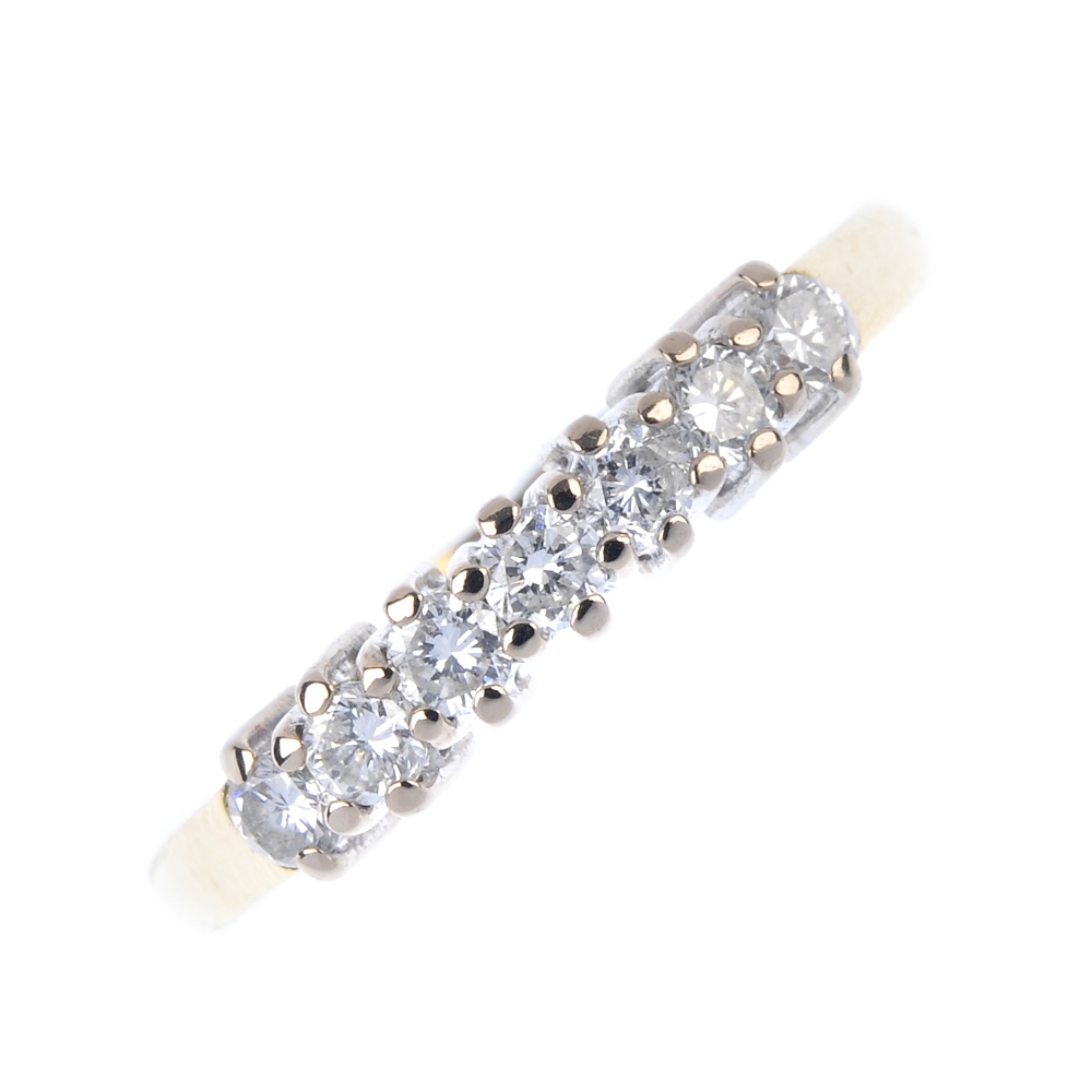 An 18ct gold diamond seven-stone ring. The brilliant-cut diamond line, to the plain band.