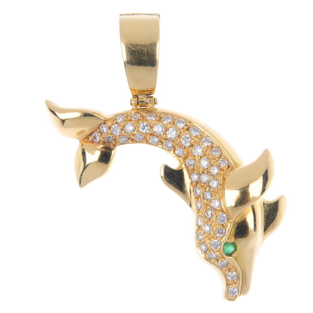 CARTIER - a diamond and emerald dolphin pendant. The pave-set diamond body, to the circular