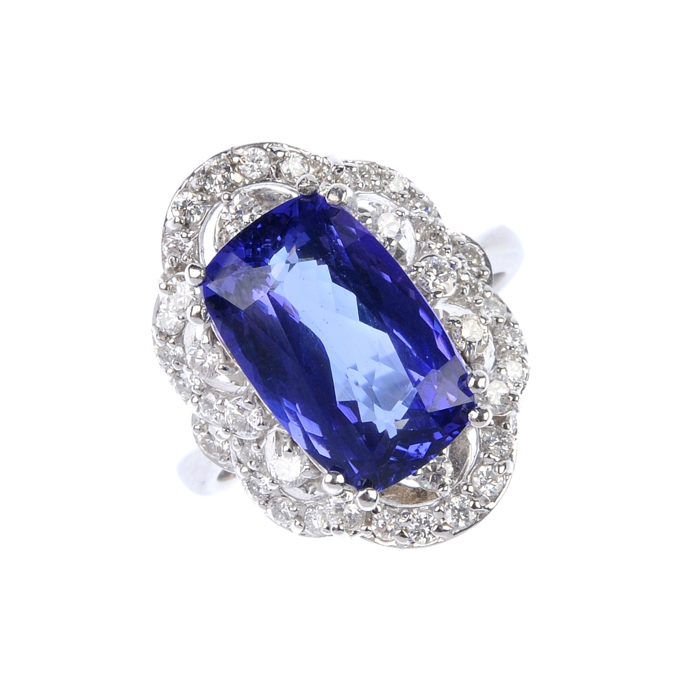 A tanzanite and diamond cluster ring. The oval-shape tanzanite, within a brilliant-cut diamond