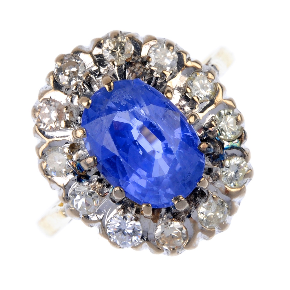 A mid 20th century 18ct gold sapphire and diamond cluster ring. The oval-shape sapphire, within a