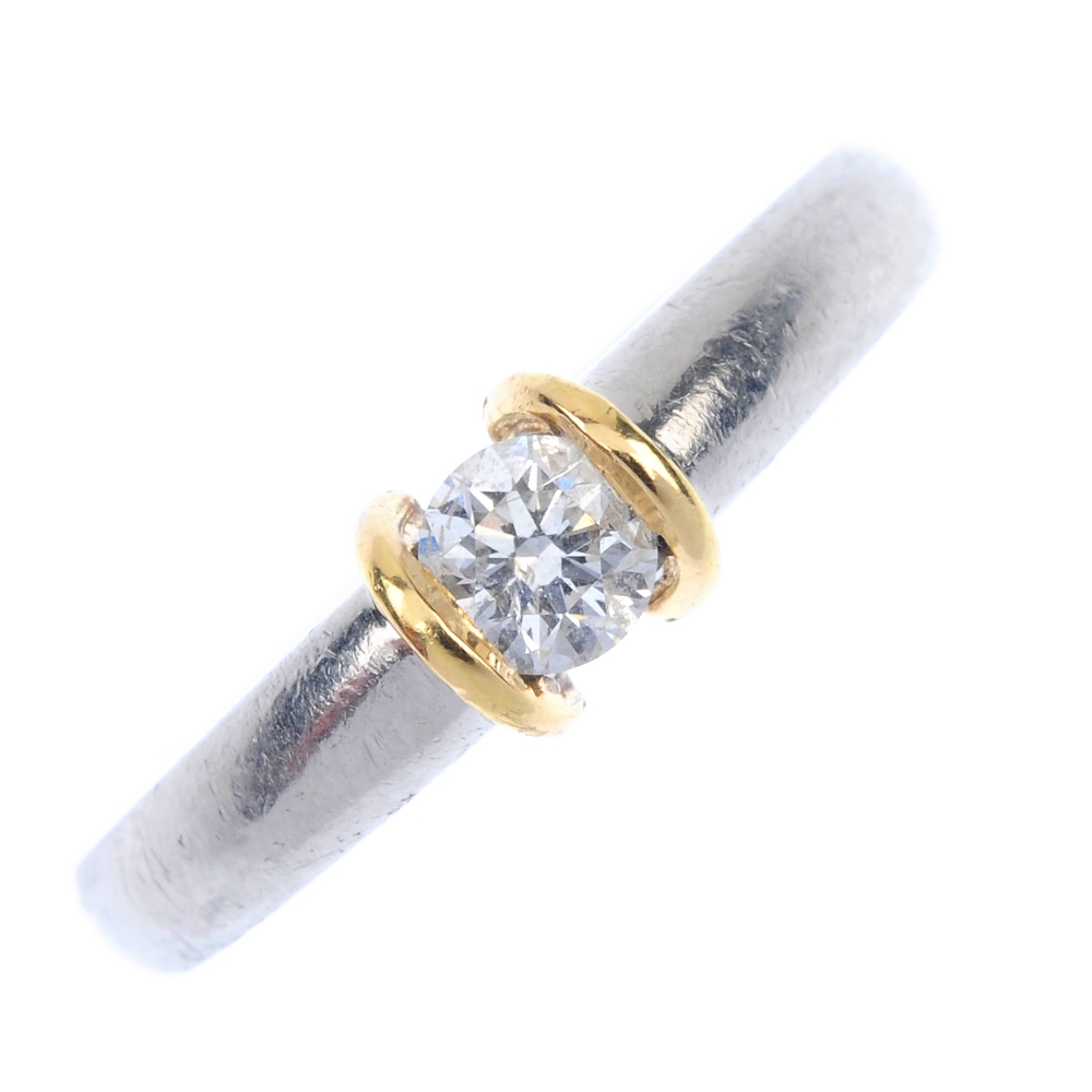 A platinum diamond single-stone ring. Of bi-colour design, the brilliant-cut diamond, with raised