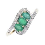 A 9ct gold emerald and diamond crossover dress ring. The three oval-shape emeralds, to the single-